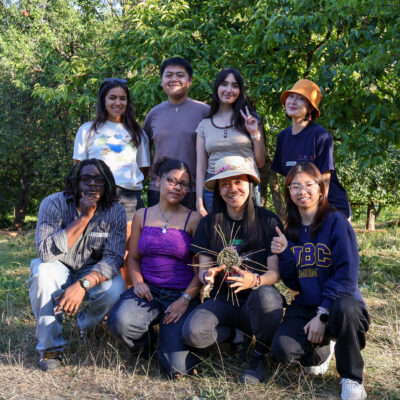A group of youth participants smiling and posing for a photo in a garden.