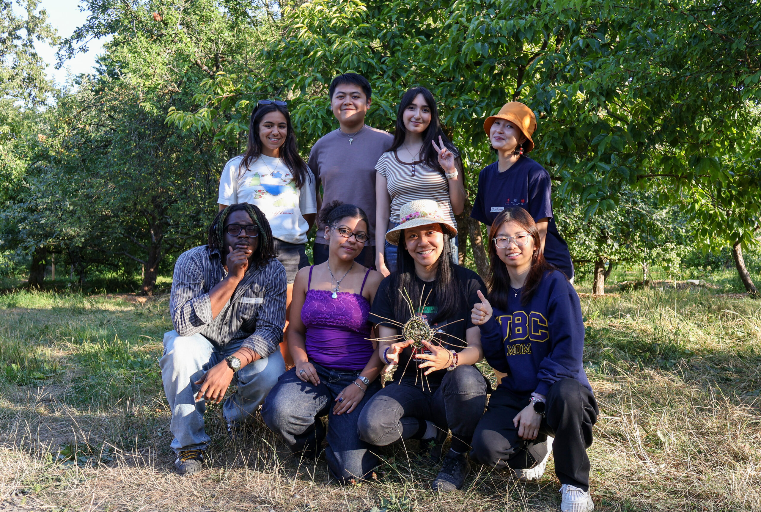 A group of youth participants smiling and posing for a photo in a garden.