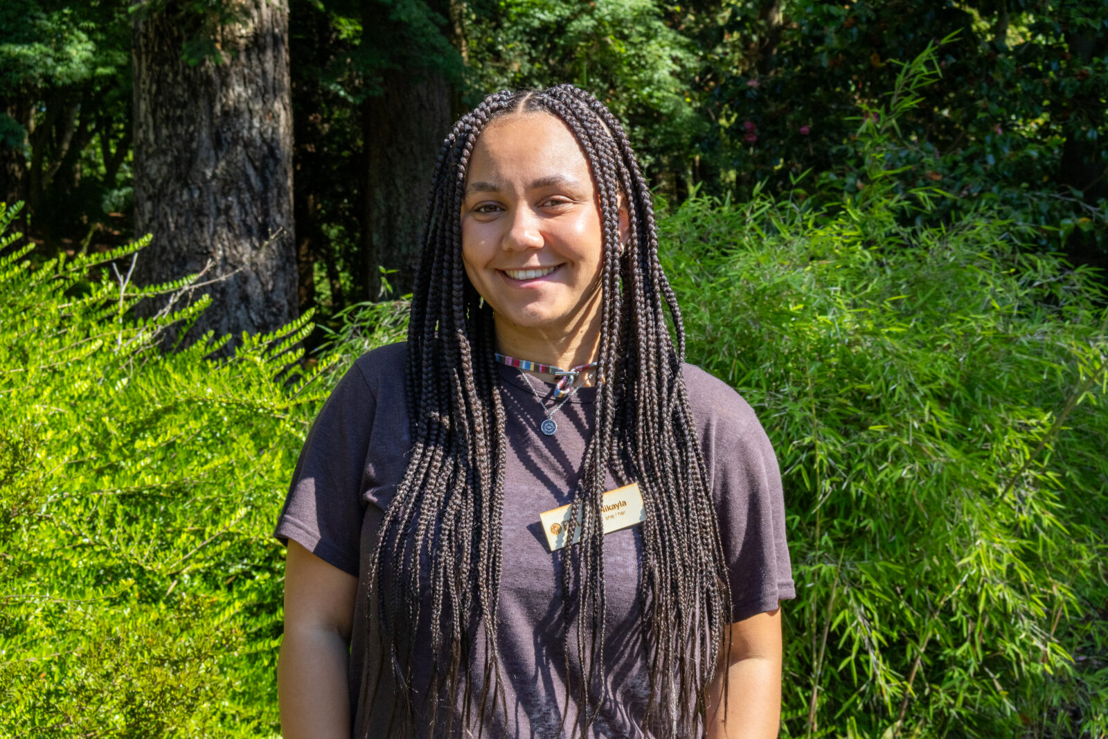 EYA staff Nikayla Allen smiling in front of greenery.